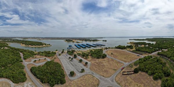 Valley Creek Aerial view of a lakeside area with a marina, roads, and lush greenery under a cloudy sky.